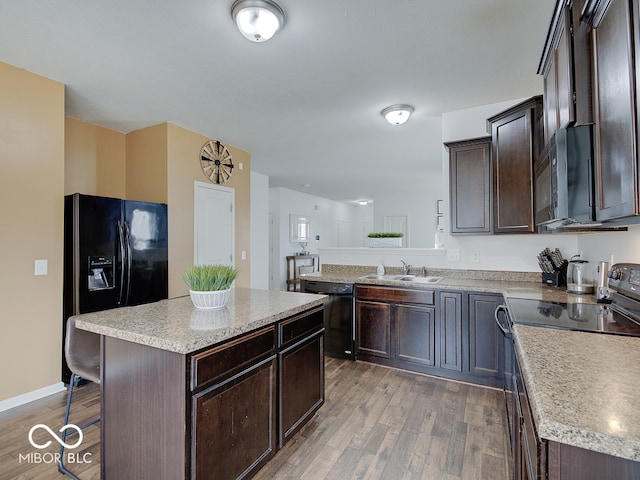 kitchen featuring light countertops, dark brown cabinetry, a sink, wood finished floors, and black appliances