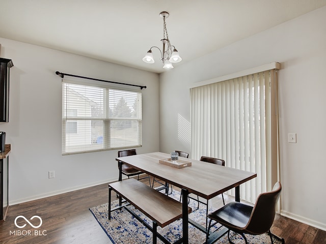 dining area with dark wood-style floors, baseboards, and an inviting chandelier