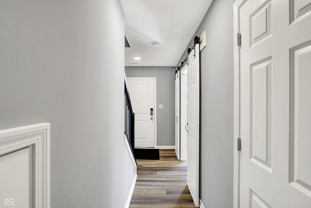 hall with dark wood finished floors, baseboards, and a barn door