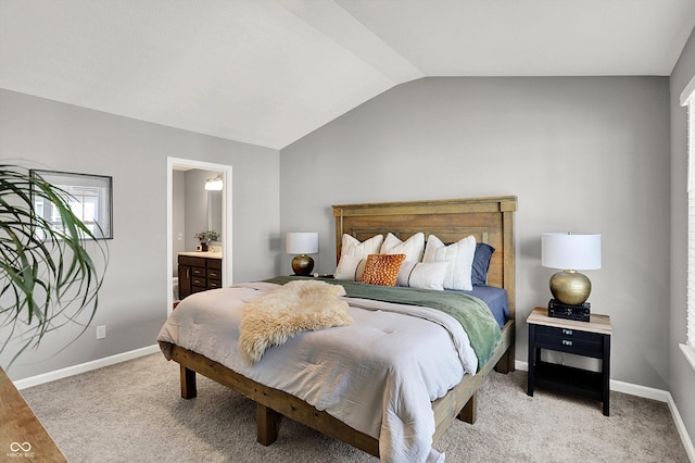 bedroom featuring lofted ceiling, light colored carpet, baseboards, and ensuite bathroom