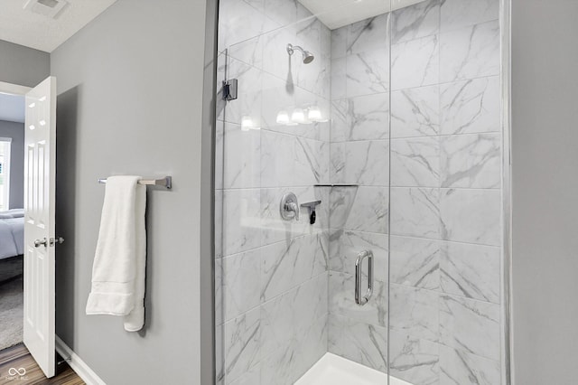 ensuite bathroom featuring visible vents, a stall shower, wood finished floors, connected bathroom, and baseboards