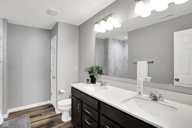 bathroom with toilet, wood finished floors, a stall shower, and a sink