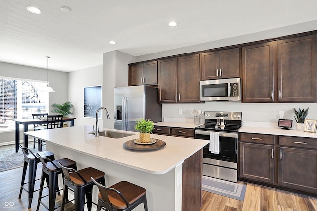 kitchen with a sink, light wood-style floors, appliances with stainless steel finishes, and light countertops