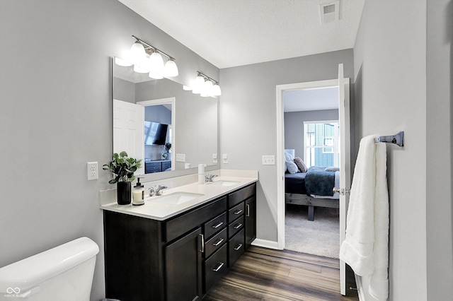 ensuite bathroom with toilet, visible vents, ensuite bathroom, and a sink