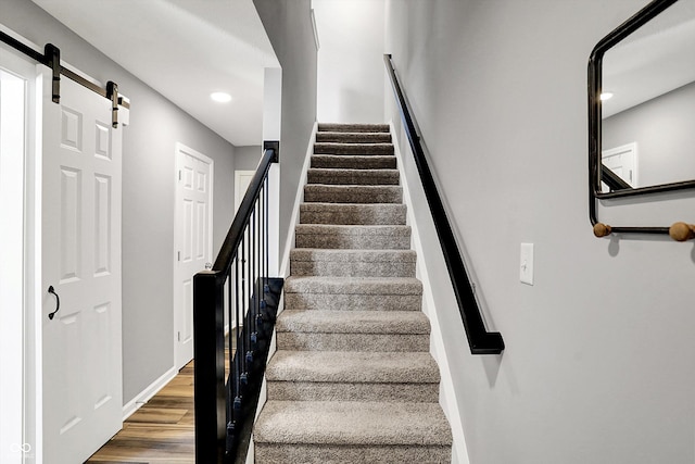 stairway with recessed lighting, baseboards, a barn door, and wood finished floors