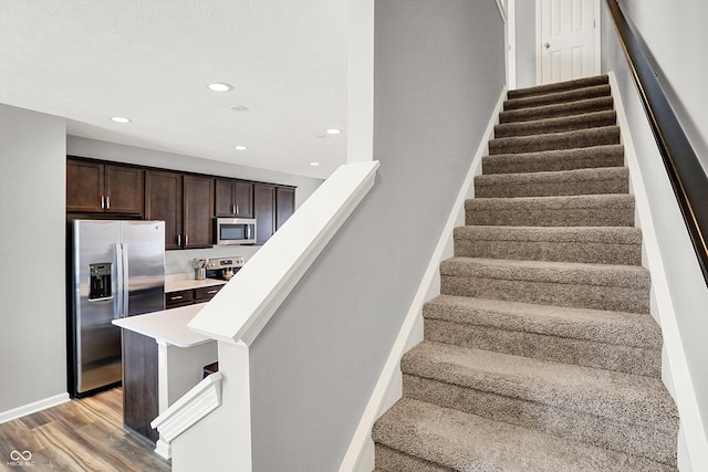 staircase with recessed lighting, wood finished floors, and baseboards