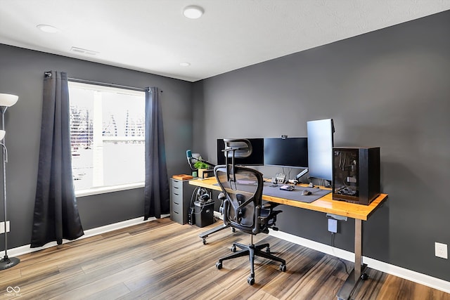 office space featuring visible vents, baseboards, and wood finished floors