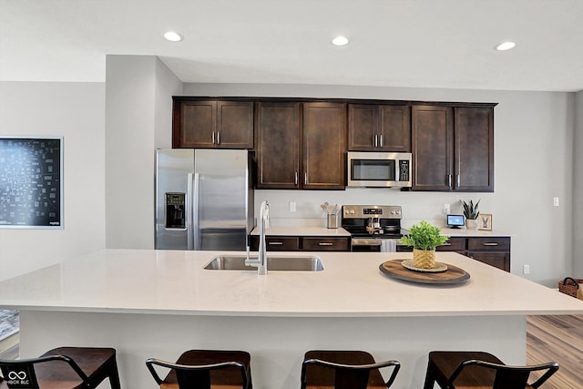 kitchen featuring a sink, dark brown cabinetry, a breakfast bar, and stainless steel appliances