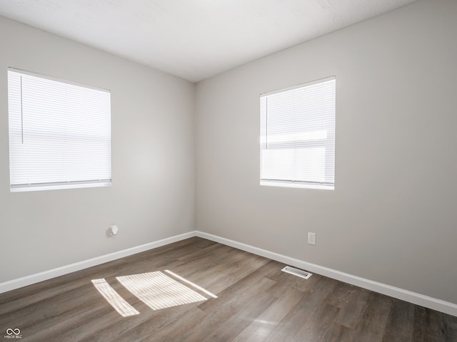 spare room with visible vents, baseboards, and wood finished floors