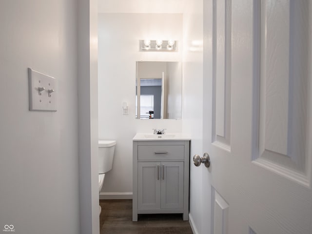 bathroom featuring wood finished floors, vanity, toilet, and baseboards