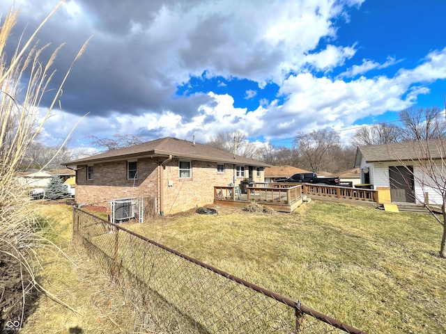 view of side of property featuring a lawn, fence, a deck, central air condition unit, and brick siding