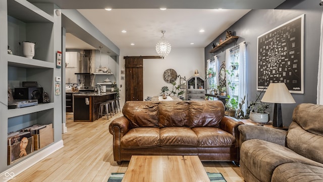 living room with a barn door, light wood-style flooring, a notable chandelier, and recessed lighting