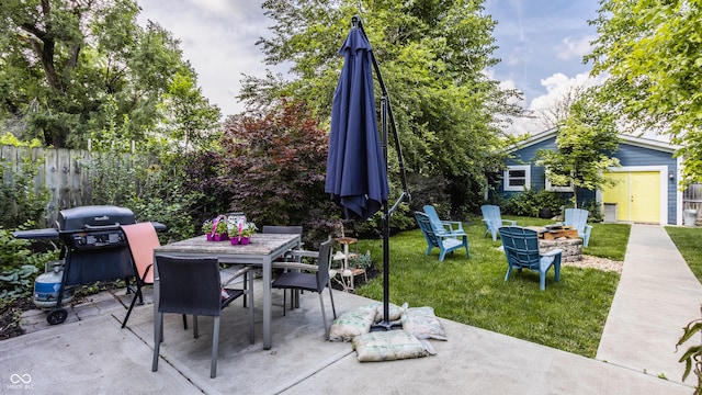 view of patio featuring an outbuilding, outdoor dining area, an outdoor fire pit, a grill, and fence