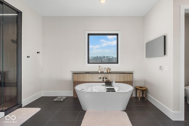 full bathroom featuring tile patterned flooring, toilet, baseboards, a soaking tub, and a shower stall