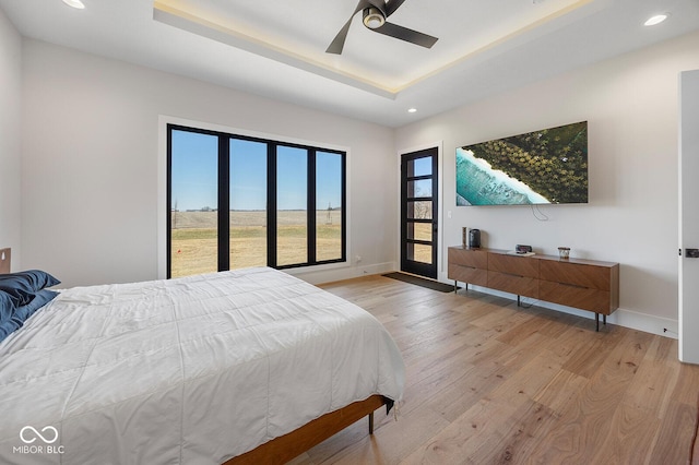 bedroom featuring recessed lighting, baseboards, a raised ceiling, and light wood-style floors