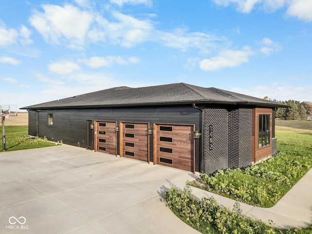 view of property exterior with a garage, roof with shingles, and driveway