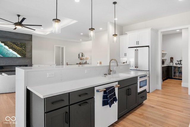 kitchen featuring white cabinetry, a sink, open floor plan, recessed lighting, and white appliances
