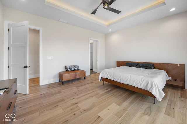bedroom featuring light wood-style floors, a tray ceiling, recessed lighting, and visible vents