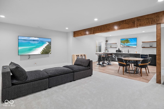 living room featuring light carpet, indoor wet bar, recessed lighting, baseboards, and light wood-type flooring