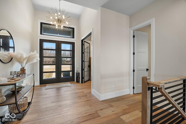 entryway featuring baseboards, a notable chandelier, french doors, and light wood-style floors