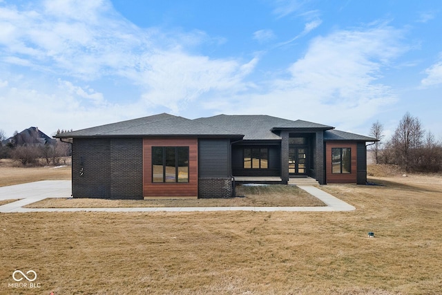 back of house featuring a lawn, brick siding, roof with shingles, and french doors