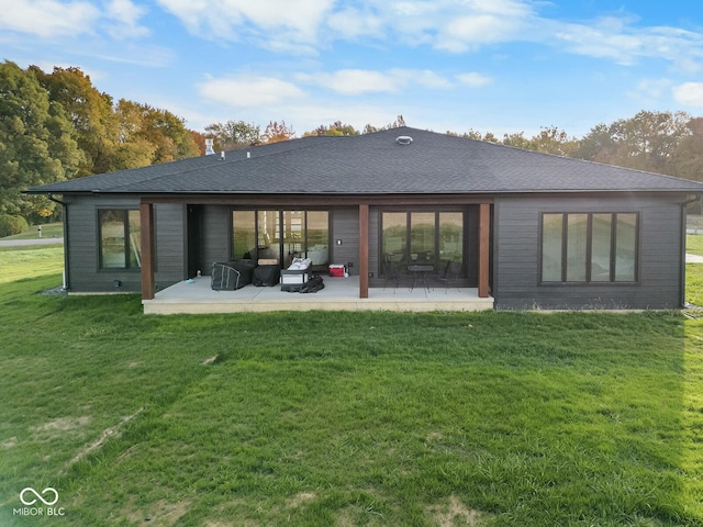 rear view of house featuring roof with shingles, a patio, and a yard
