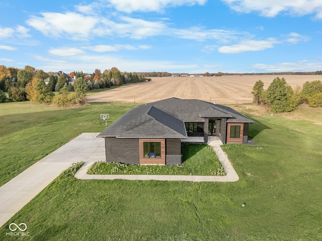 view of front of home featuring brick siding, a rural view, roof with shingles, and a front lawn