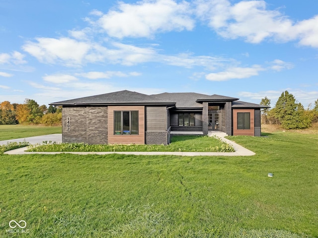 rear view of house with a lawn and brick siding