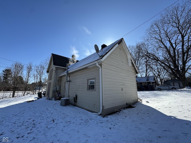 snow covered back of property with a garage and central air condition unit