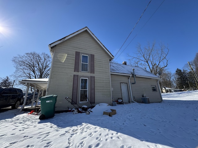 snow covered rear of property featuring cooling unit