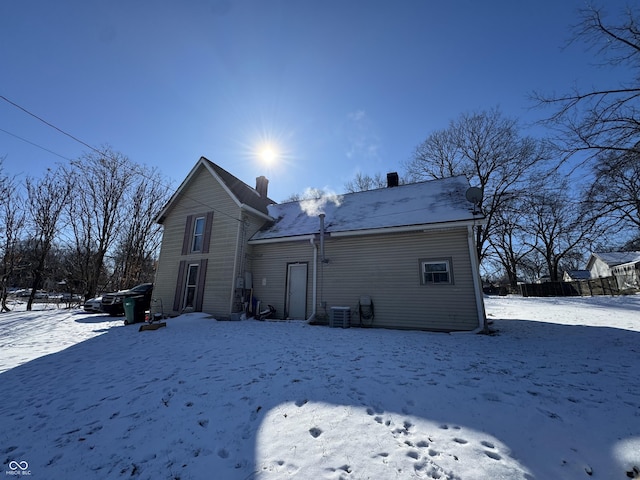 snow covered house featuring a chimney