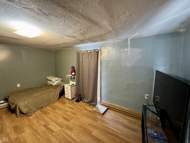 bedroom with a textured ceiling and wood finished floors