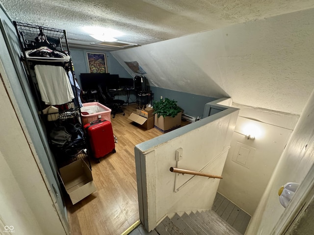 interior space with a textured ceiling, wood finished floors, and lofted ceiling