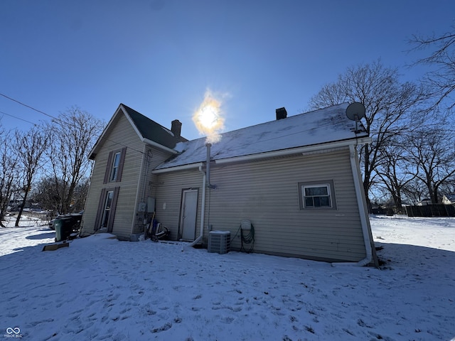 snow covered rear of property with central AC unit