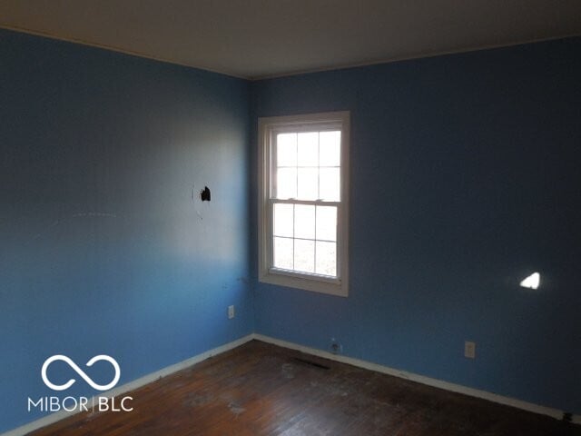 spare room with dark wood-style flooring and baseboards