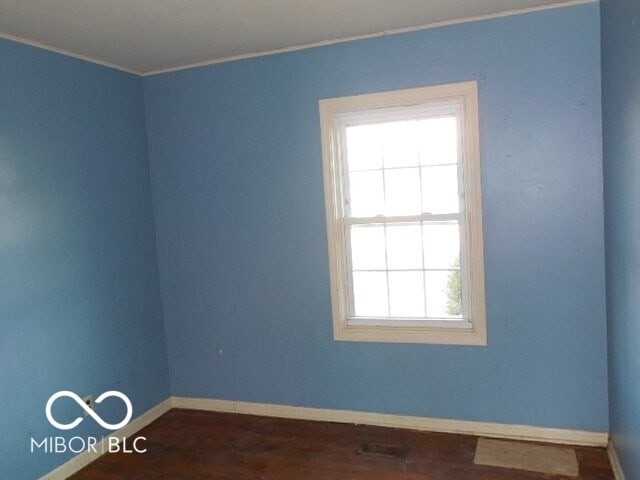 empty room with baseboards, visible vents, and dark wood-type flooring