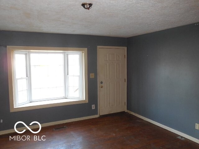 entrance foyer featuring a healthy amount of sunlight, visible vents, baseboards, and wood finished floors