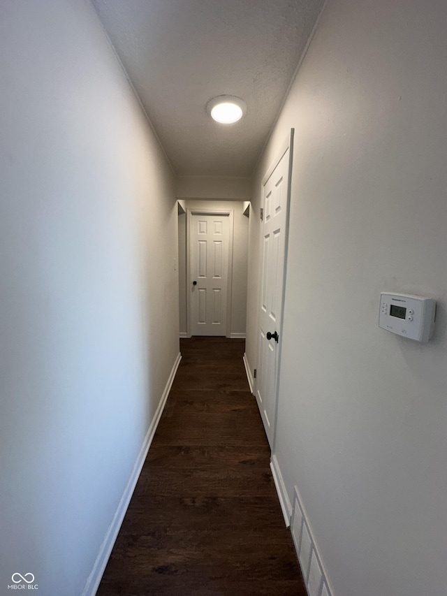 corridor with baseboards, visible vents, and dark wood-style flooring