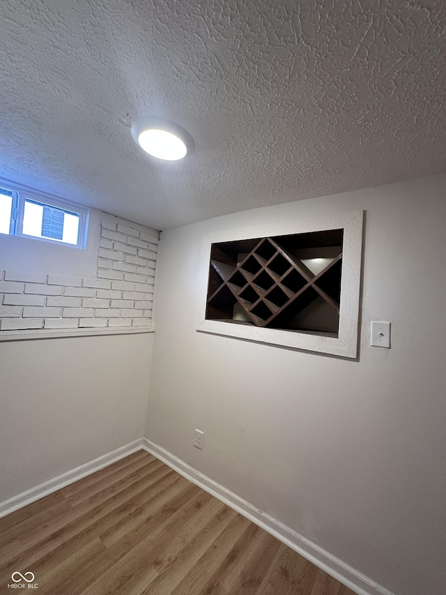 empty room with a textured ceiling, baseboards, and wood finished floors