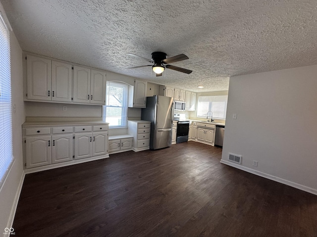 kitchen with light countertops, appliances with stainless steel finishes, dark wood-type flooring, and visible vents