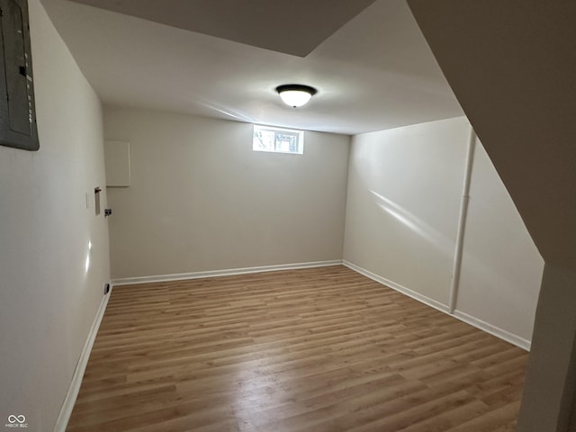 basement with electric panel, baseboards, and wood finished floors