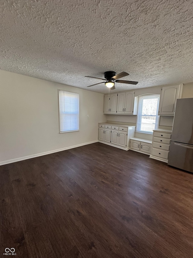 interior space featuring ceiling fan, dark wood-type flooring, a textured ceiling, and baseboards