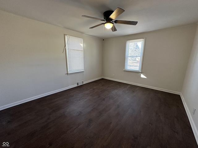 spare room with baseboards, visible vents, ceiling fan, and dark wood-type flooring