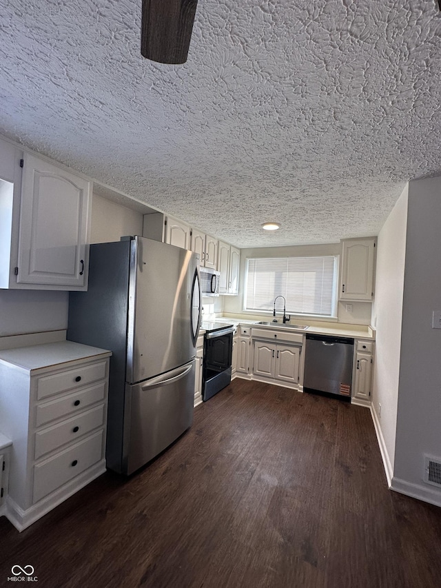 kitchen featuring dark wood-style floors, light countertops, appliances with stainless steel finishes, and a sink