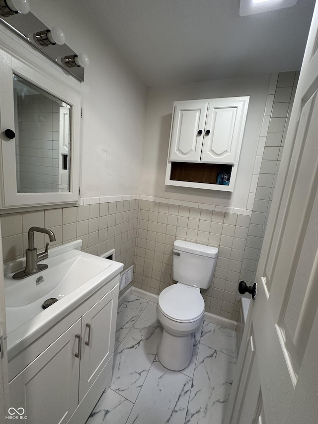 bathroom featuring marble finish floor, wainscoting, vanity, and toilet