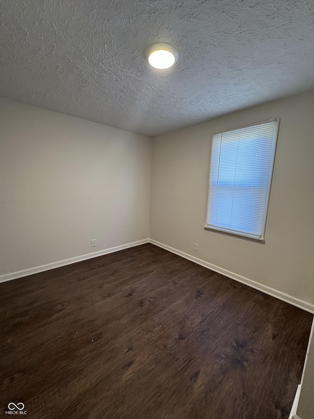 unfurnished room featuring dark wood-style flooring, a textured ceiling, and baseboards