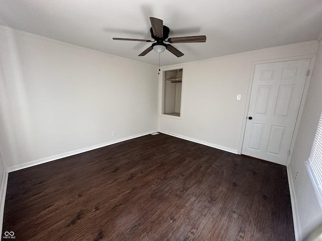 empty room with dark wood finished floors, crown molding, baseboards, and ceiling fan