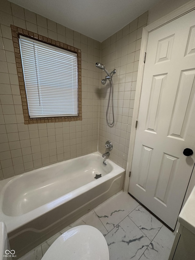 bathroom featuring marble finish floor and shower / tub combination