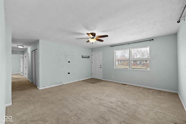 carpeted spare room with attic access, visible vents, baseboards, ceiling fan, and a textured ceiling