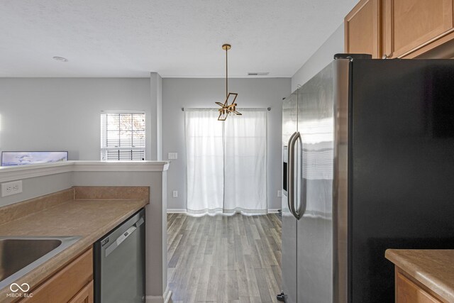 kitchen featuring visible vents, appliances with stainless steel finishes, brown cabinetry, light wood-style floors, and a textured ceiling